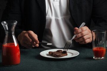 man at dinner consisting of delicious grilled beef steak and bright red tomato juice poured into a glass