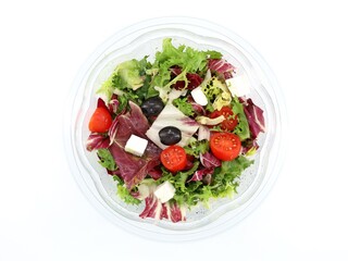 Healthy  mixed salad  in a transparent bowl. The ingredients are lettuce,  radicchio, crisphead, cherry tomatoes, black olives and soft cheese cubes. Top view on white background