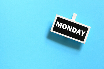 The word MONDAY on a small chalk board over a blue background.