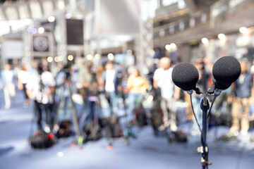 Microphone in focus at media event, press or news conference, blurred video camera operators in the...