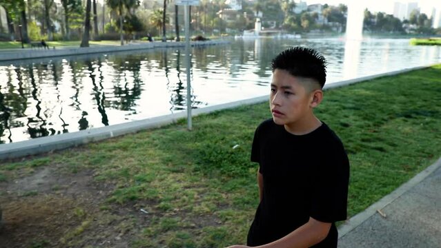 14 year old boy jogs around a small lake in Los Angeles. Los Angeles skyline can be seen in the distance.