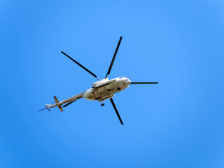 Ambulance helicopter flying against a clear blue sky. Bottom view.