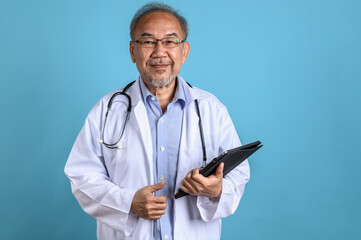 Studio portrait photo of senior male Asian doctor on blue background with copy space background.