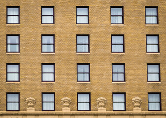 Many windows in row on facade of urban apartment building. Brick building.