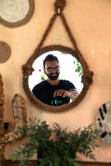 Handsome brown-haired boy with a beard, taking pictures of himself in a mirror on a terrace because it is the photography day.