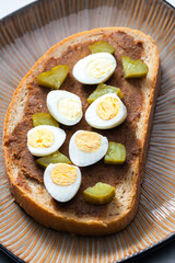 cracklings spread with pickled cucumber and boiled egg on slice of bread