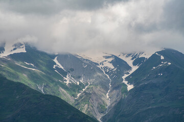 Fototapeta premium Clouds over the snow covered mountains. High mountains peak, winter landscape.