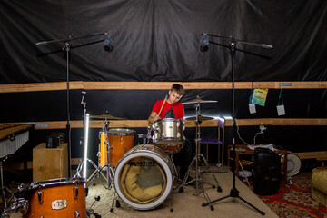 Fototapeta premium a young drummer plays drums, cymbals with sticks, sitting on a special chair