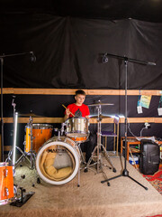 a young drummer plays drums, cymbals with sticks, sitting on a special chair