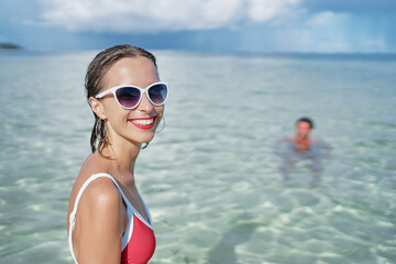 Enjoying suntan and vacation. Outdoor portrait of pretty young woman in swimsuit on tropical beach.