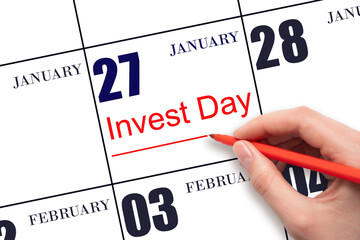 Hand drawing red line and writing the text Invest Day on calendar date January 27. Business and financial concept.