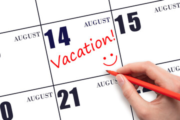 A hand writing a VACATION text and drawing a smiling face on a calendar date 14 August. Vacation...