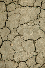 Parched earth that is cracked gray, it hasn't rained for a long time. The texture of the soil.