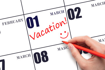 A hand writing a VACATION text and drawing a smiling face on a calendar date 1 March. Vacation...