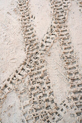 trail of motorcycle tires in the sand.