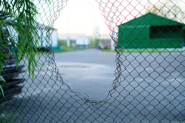 Hole in the fence. Mesh wire boundary. Steel mesh barrier fence. Chain link fence with Hole.