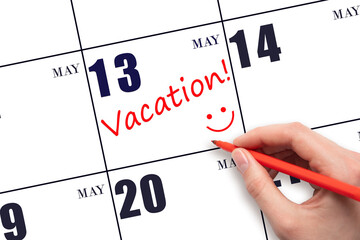 A hand writing a VACATION text and drawing a smiling face on a calendar date 13 May. Vacation...