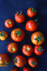 Fresh organic tomatoes, picked from the garden, on dark background. Flat lay.