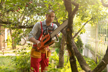 Obraz premium handsome young man gardener trimming hedgerow in a garden park outdoor.