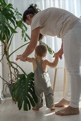 Vertical shot of the young kid gently touch home plants with care, while exploring world and nature with his mother. Nature education, montessori and observation skills concept © Alla