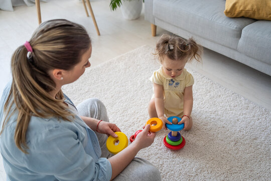 Beautiful toddler girl play with a wooden toys at home. Baby play with a colour educational wooden toys. Child play with her mother at home. Child development concept