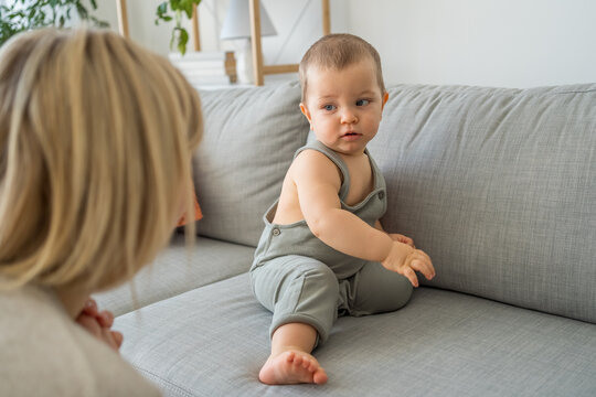 Family time concept. Happy caucasian mother and her child son sitting on sofa and looking at each other. Boy relaxing with his mother. Lazy weekend concept. Stock photo