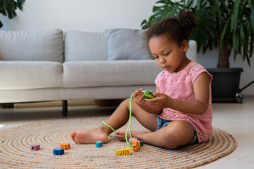 Horizontal view of the black female kid toddler playing wooden toys at home. Cute little kid...