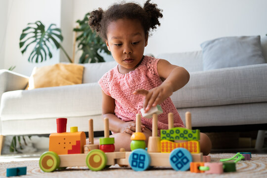 Black kid playing with colourful railway station at home. Little african american baby having fun with ecological train toy. Educational and creative toys and games for young children concept