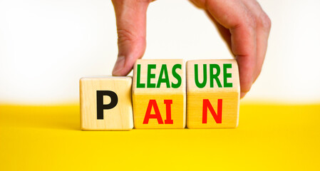 Pain or pleasure symbol. Concept words Pain or Pleasure on wooden cubes. Businessman hand. Beautiful yellow table white background. Business and pain or pleasure concept. Copy space.