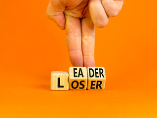 Loser or leader symbol. Concept words Loser or leader on wooden cubes. Businessman hand. Beautiful orange table orange background. Business and loser or leader concept. Copy space.