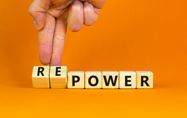 Power or repower symbol. Businessman turns wooden cubes and changes concept words Power to Repower. Beautiful orange table orange background. Business ecological power or repower concept. Copy space.