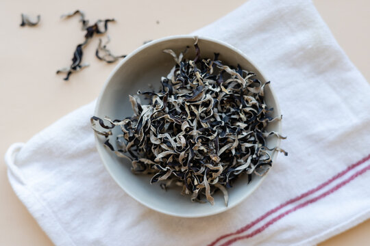 Dried mun mushrooms, Chinese traditional medicine and cuisine. Fungi ingredients in plate on beige background