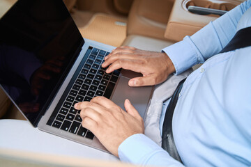 Businessperson working on portable computer in car