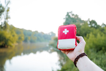 A small red bag with a white cross, a man holding a first aid kit in his hand, a track to help with injury a bag with medicines first aid kit.