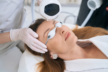 Patient in cosmetology center undergoes a forehead skin rejuvenation procedure - obrazy, fototapety, plakaty