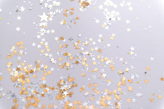 golden confetti stars on grey background top view