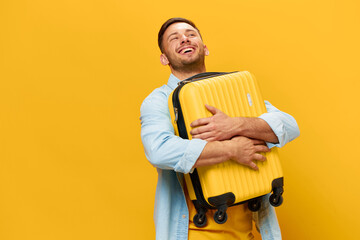 Enjoyed funny smiling tanned handsome man in blue shirt hugs hold suitcase ready for vacation...