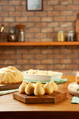 Brazilian chiken croquette (coxinha de frango) on a wooden table and a bricks kitchen background.