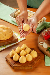 Woman hands preparing brazilian croquette (coxinha de frango) on a wooden table.