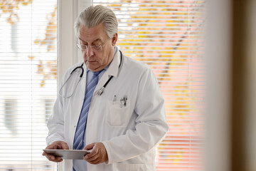 Arzt hält in seiner Praxis einen Tablet Computer in der Hand