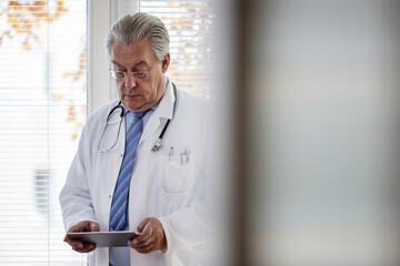 Arzt hält in seiner Praxis einen Tablet Computer in der Hand