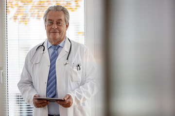 Arzt hält in seiner Praxis einen Tablet Computer in der Hand