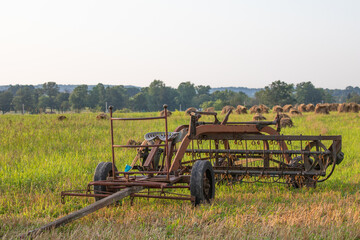 Amish style hay rake sitting in a farm field with wheat shocks in the background