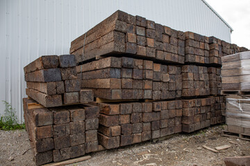 Large stack of railroad ties sitting beside a large metal building