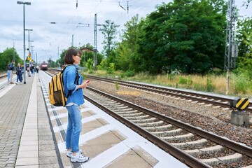 Fototapeta premium Woman passenger waiting for commuter train at station outdoor platform