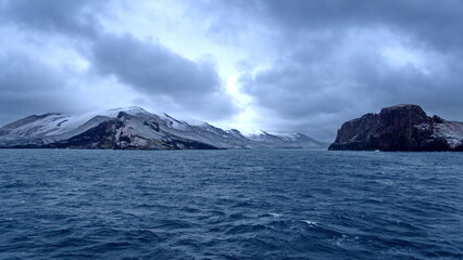 Snow dusted mountains around the pass at the entrance to the crater bay in Deception Island,...