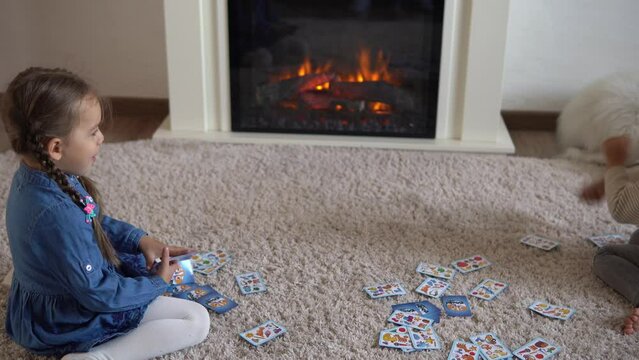 Childhood, education, isolation. Relaxing resting at home. Two little smart preschool children relax play playing cards on carpet floor. Two Kids brother sister friends have interest in gambling games