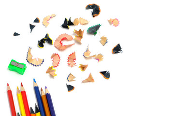 Sharpener and set colored pencils with wooden shavings white background.