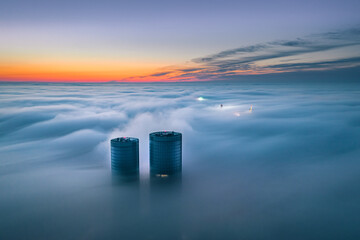 
Skyscraper rooftop over the clouds at sunrise. Thick fog covers the Riga city, and warm sunlight...