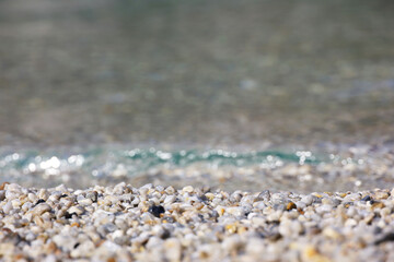 Small pebble stones on sea beach with transparent water. Background for summer vacation